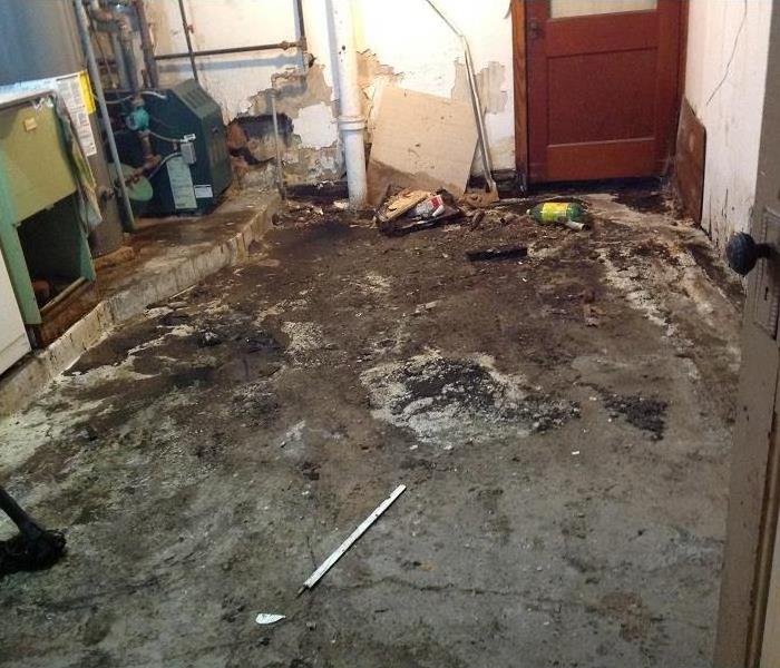 A basement laundry room with sewage on the concrete floors.