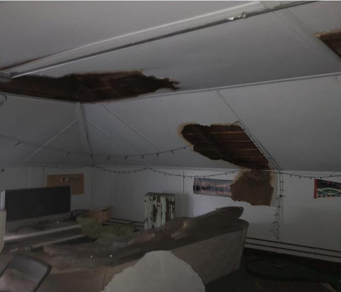 Attic with two large burns on the walls and ceiling while furniture is still in the room.